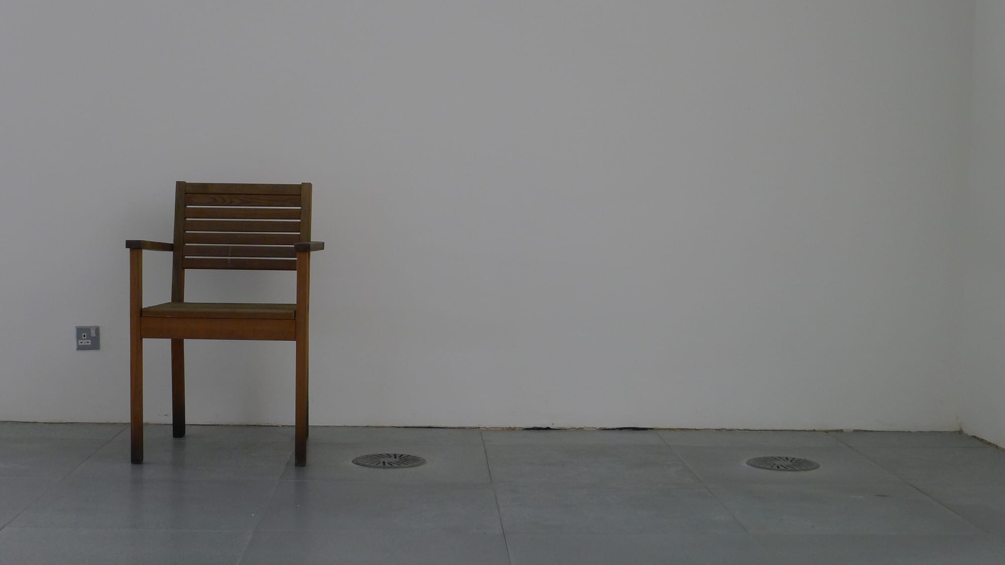 A photo of a single chair against a white wall