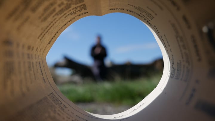 A photo taken through a curled up book page with someone in the distance