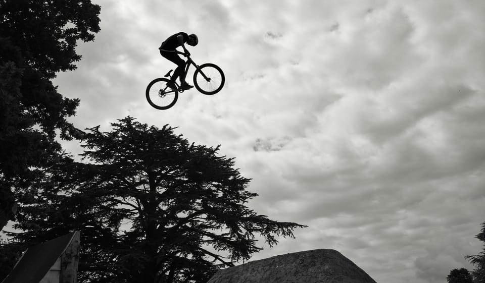 Someone on a mountain bike, high in the air, jumping over a ramp 