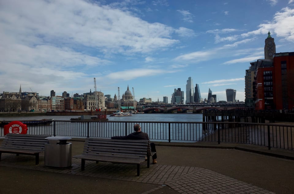 A man sitting on a bench by the River Thames, London
