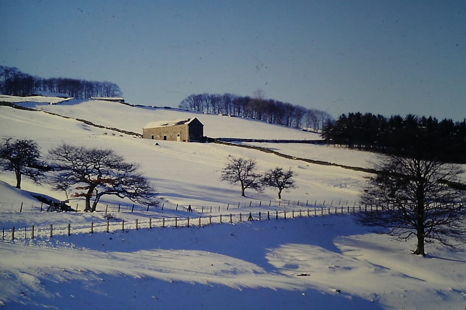 A photo of an old barn on a winter hillside