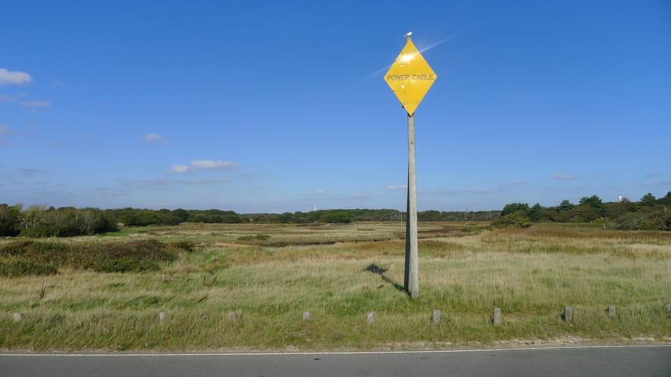 A photo of a lone power cable sign in a field
